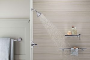 A closet-up image of a walk-in shower with water spraying from the showerhead.